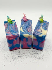 Three blackberry sippy soap bars with blue and pink swirls, each topped with a small charm