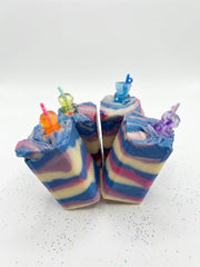 A group of handmade blackberry sippy soap bars with swirled blue and pink tops and charm toppers
