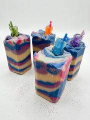 A group of blackberry sippy soap bars with charm toppers on a white background