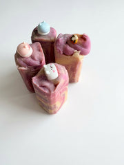 A group of bedtime honey soap bars in pink and cream swirls, each with a charm topper