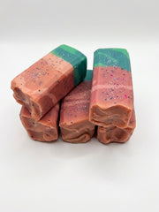Handmade watermelon soap bars with coral flesh, green rind and poppy seed pips, on a white background