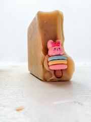 A goat milk and oat soap bar standing upright with a pastel topper