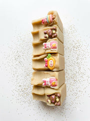 A row of goat milk and oat soap bars with small decorative toppers