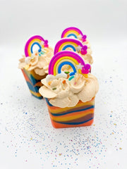 Rainbow striped kids' soap bars in a row, each with a piped top and a rainbow topper
