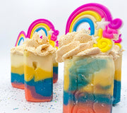 A group of rainbow striped handmade soap bars with piped cream tops and rainbow toppers