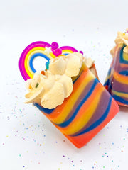 A single rainbow striped soap bar with a piped swirl top and a rainbow topper